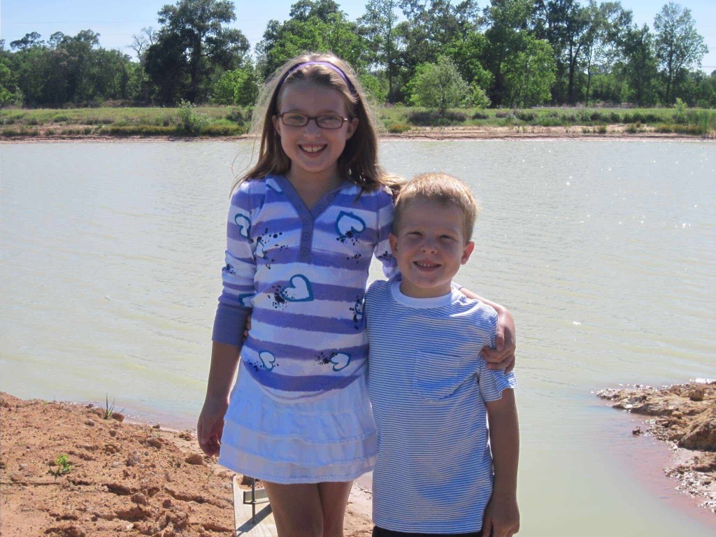 a photo of Eric and Taylor posed for their Kindergarten and 3rd grade picture. Taylor has her arm around Eric and they are both wearing big smiles for the camera.