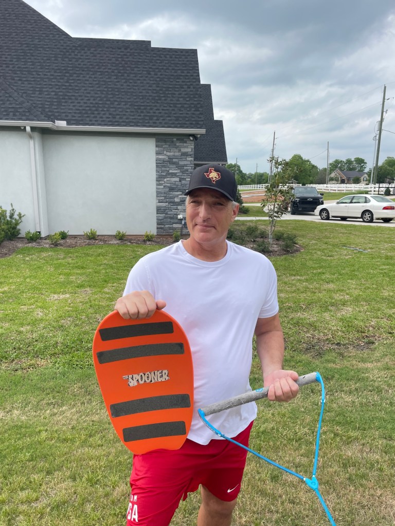 Mike stands holding his orange and black striped spooner in his right hand with the handle in his left.